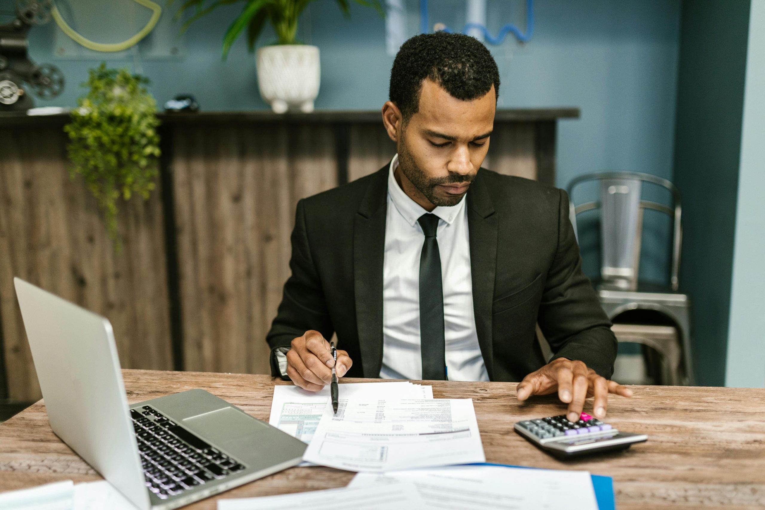 A focused businessman works with a calculator and documents in a modern office.